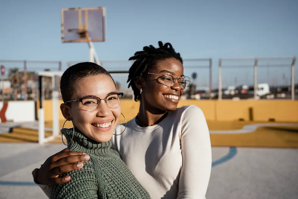 Mulheres negras e brancas abraçadas em um telhado