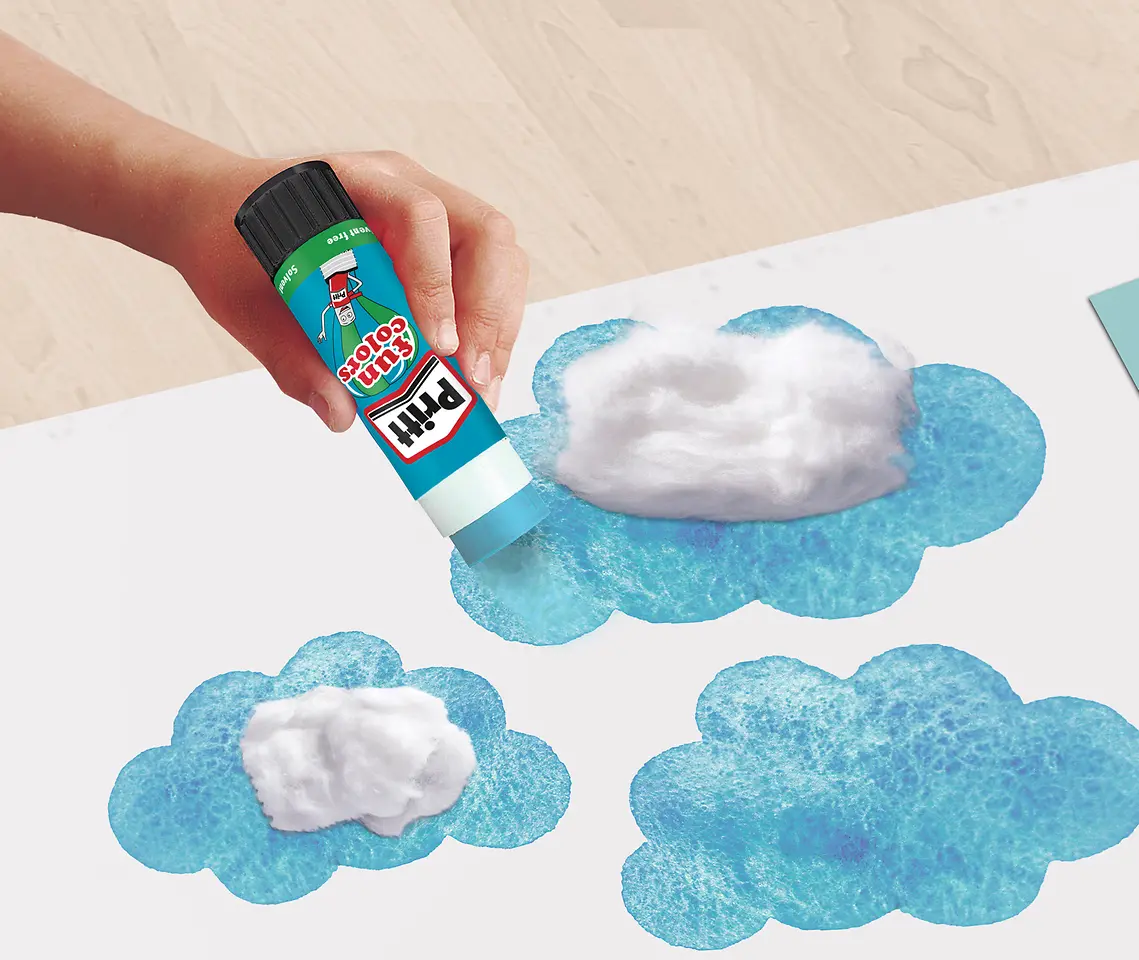 Uso da Cola Pritt Fun Color azul em um trabalho artístico com algodão e desenho de uma nuvem em um papel branco.