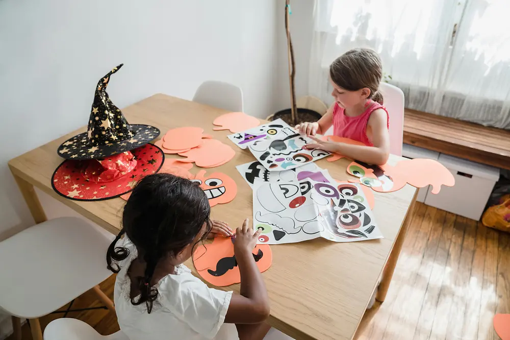 Crianças praticando atividades de colagem para decoração do Halloween